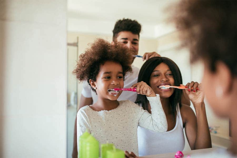 Family brushing their teeth in front of mirror